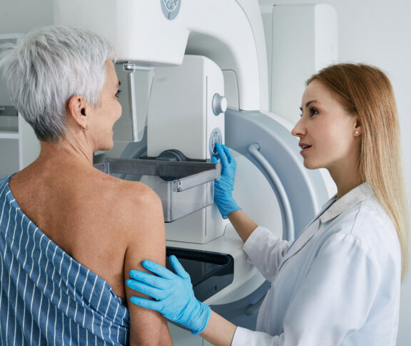 Senior woman having mammography scan at hospital with medical technician. Mammography procedure, breast cancer prevention