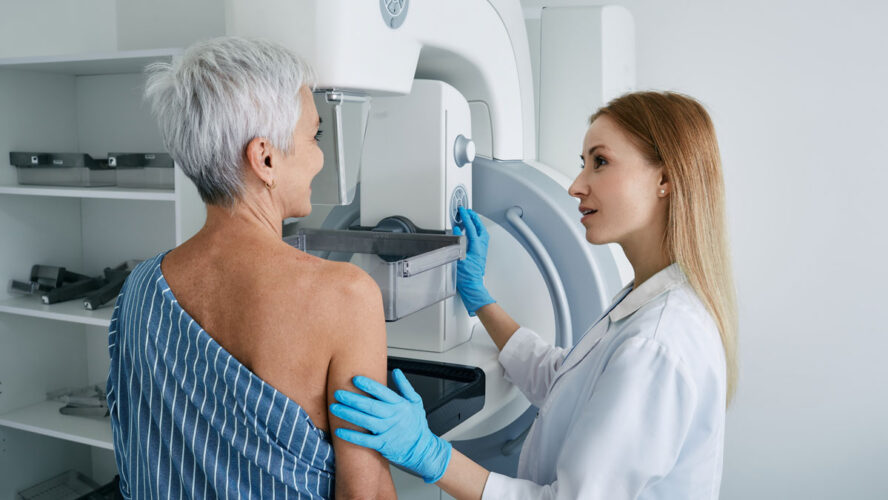 Senior woman having mammography scan at hospital with medical technician. Mammography procedure, breast cancer prevention