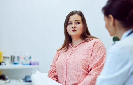 A sad adult overweight woman talking with a female doctor at the clinic.
