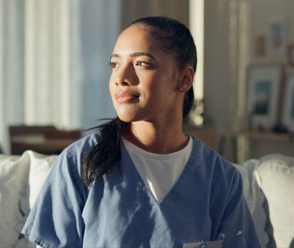 Calm, thinking and a nurse or woman on the sofa to relax from a career in healthcare in a house. Smile, peace and a medical employee or doctor with an idea or vision on the couch for a memory