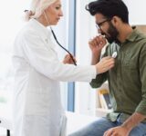 Elderly woman in white lab coat checking lungs and heart via stethoscope
