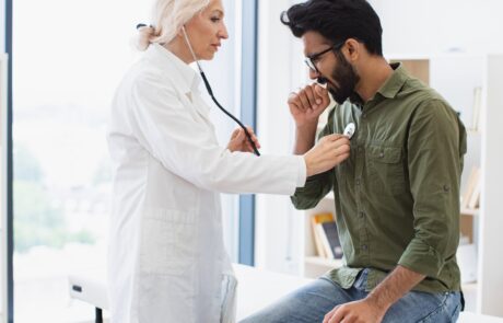 Elderly woman in white lab coat checking lungs and heart via stethoscope