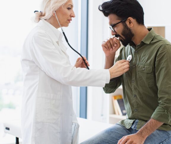 Elderly woman in white lab coat checking lungs and heart via stethoscope