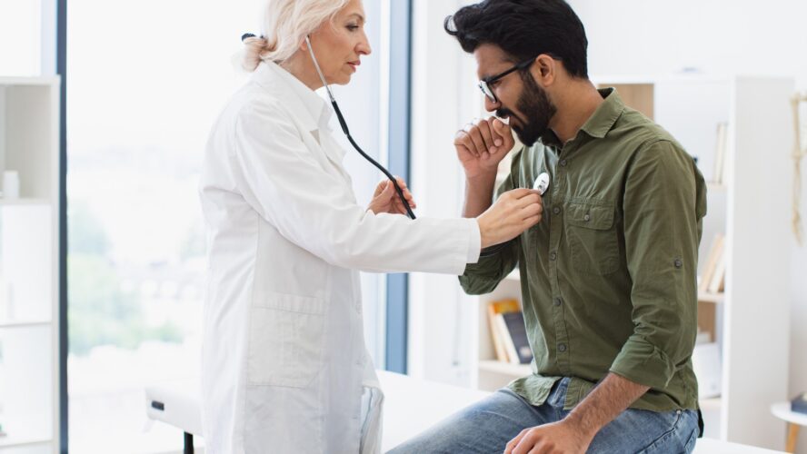 Elderly woman in white lab coat checking lungs and heart via stethoscope