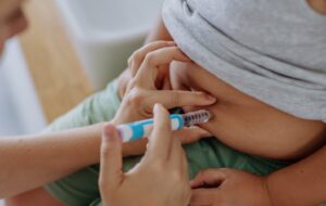 Mother of diabetic boy injecting insulin in his belly