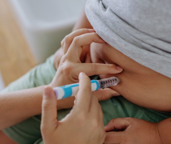 Mother of diabetic boy injecting insulin in his belly