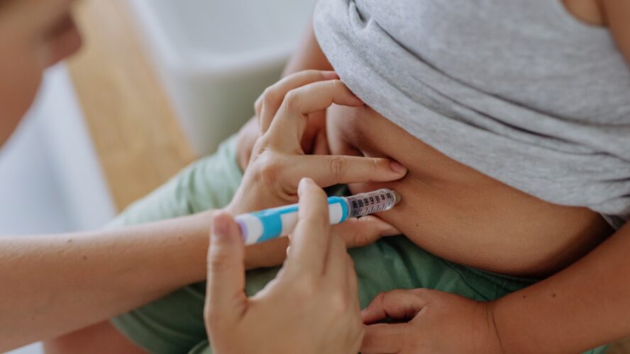 Mother of diabetic boy injecting insulin in his belly