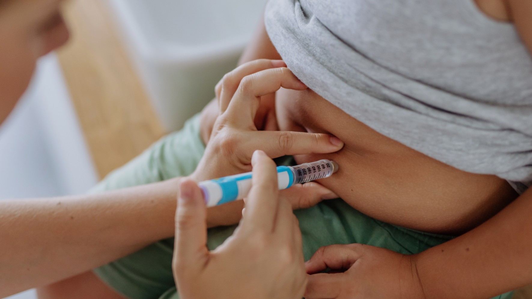 Mother of diabetic boy injecting insulin in his belly