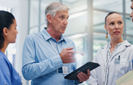 Doctors, group and tablet for hospital management with discussion for funding, planning and review. Director, leader and team with surgeon, nurse and feedback with application at wellness