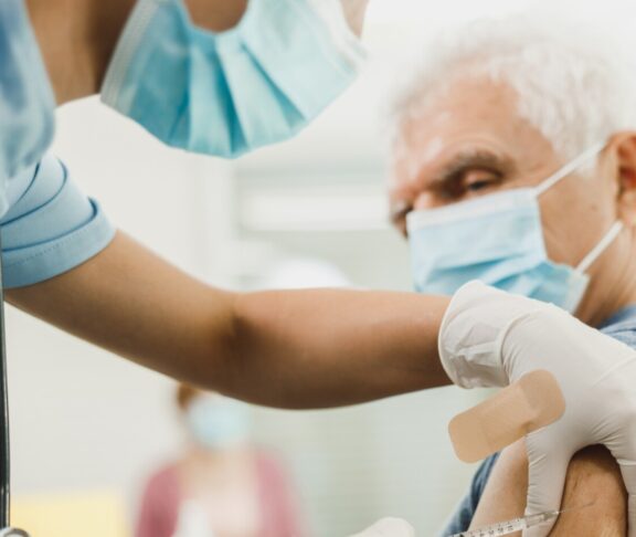 A nurse giving a vaccine to senior man