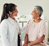 Clinic, doctor and check up with mature woman, discussion and healthcare, service and consultation. Hospital, caregiver and person with patient in office, test and support of medical professional