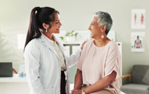 Clinic, doctor and check up with mature woman, discussion and healthcare, service and consultation. Hospital, caregiver and person with patient in office, test and support of medical professional