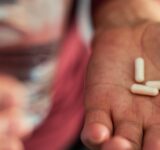 Senior man taking a pill in a bathroom
