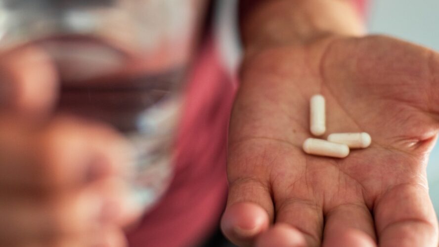 Senior man taking a pill in a bathroom