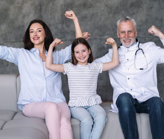 Happy family doctor, girl patient and mother showing strong gesture by arm