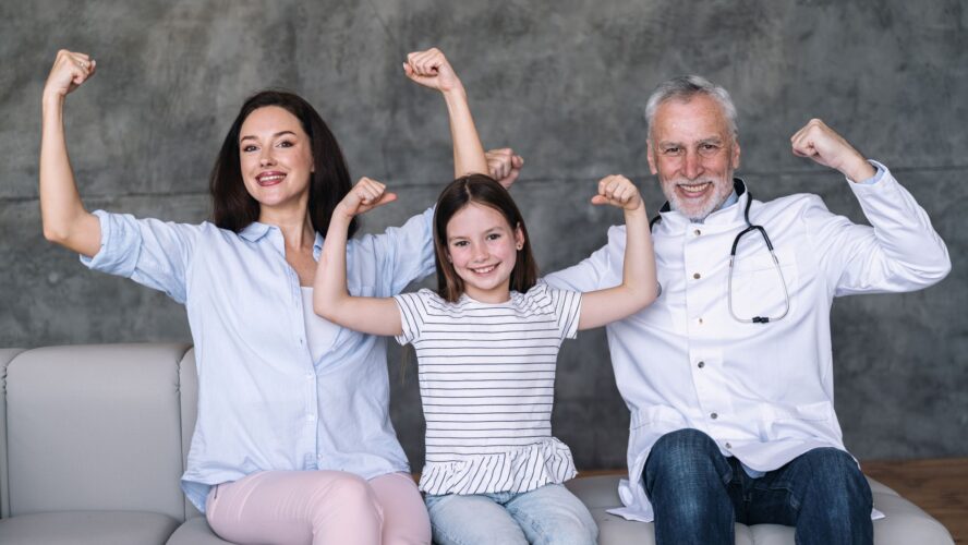 Happy family doctor, girl patient and mother showing strong gesture by arm