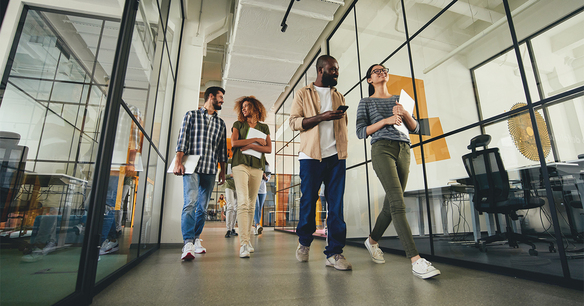 men and women carrying their laptops while walking to the workplace