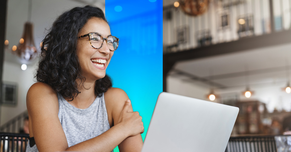 Happy woman sits at a laptop in a cafe