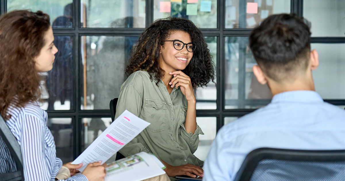 Diverse smiling happy colleagues listening to mentor leader in modern office