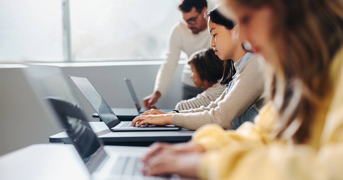 Learning to code with confidence: Male teacher helping children master programming skills