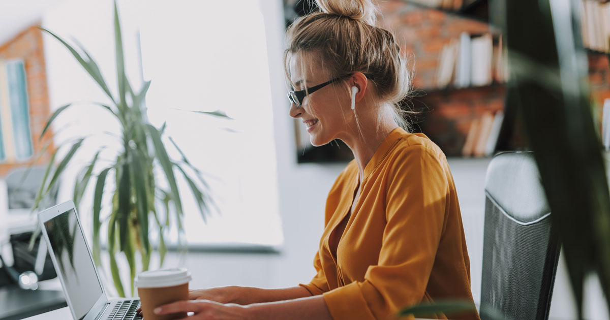Smiling woman touching cup of coffee on the table while working