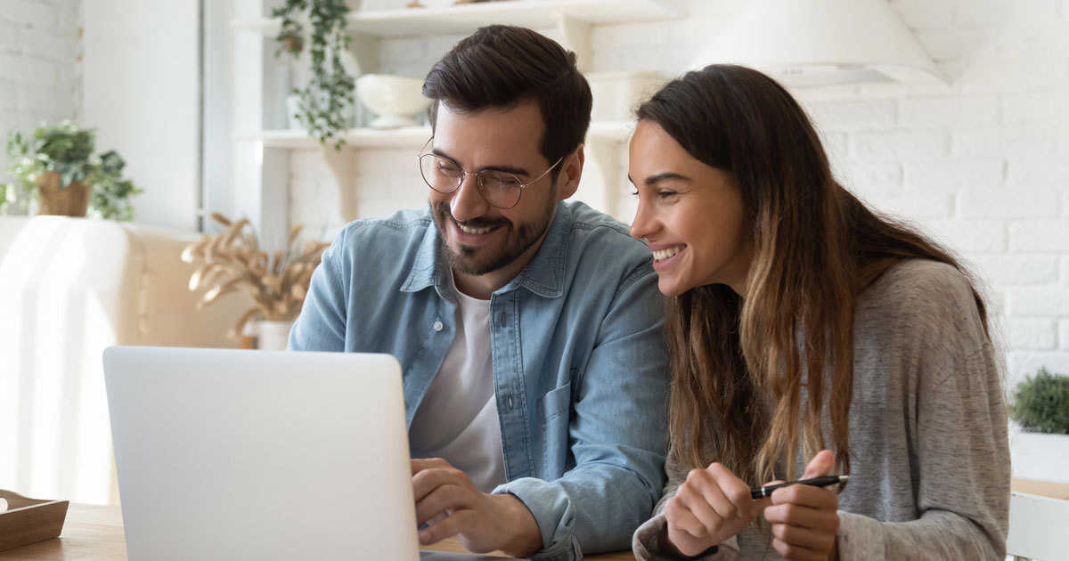 Happy young couple paying bills online in computer app