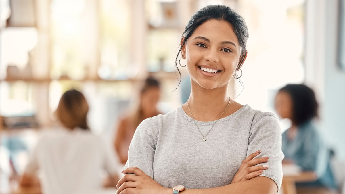 Business woman, designer and portrait of happy employee working, arms crossed and marketing agency, startup and creative company. Smile, happiness and young employee internship at advertising agency