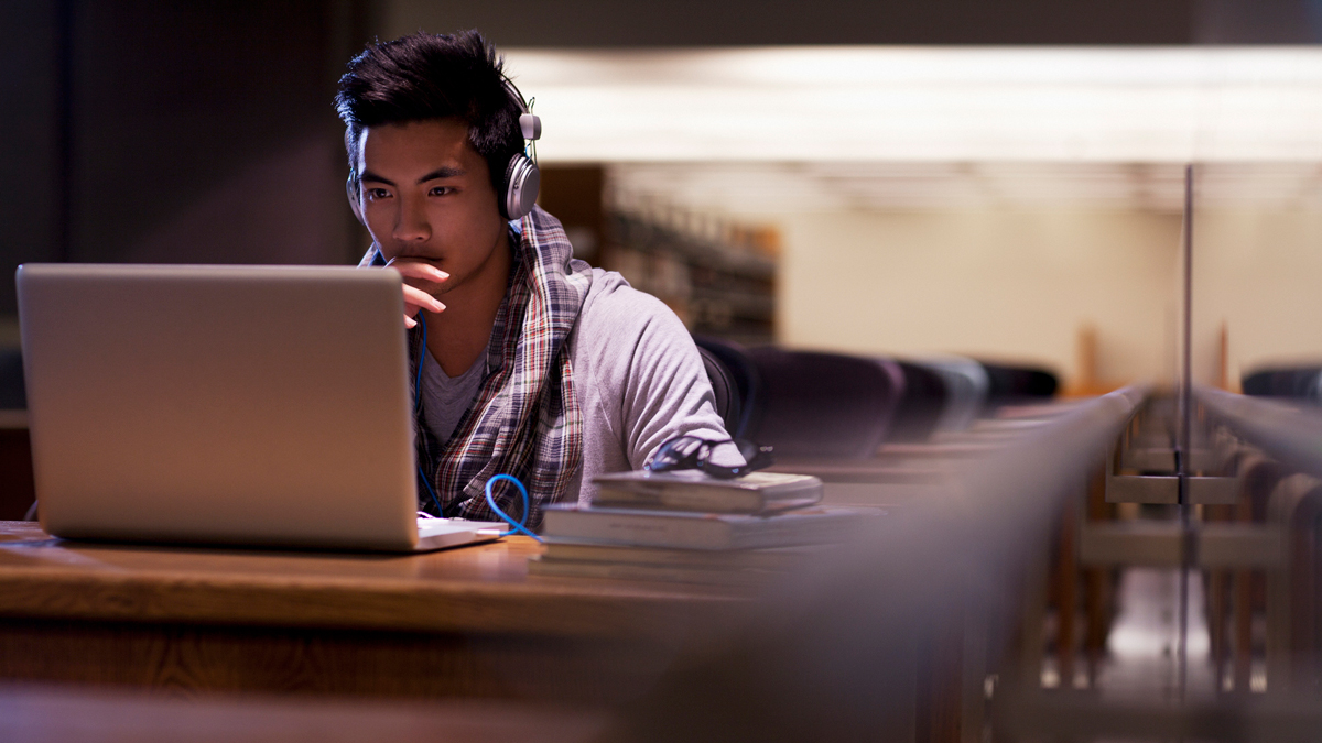 Student working on laptop in library - stock photo