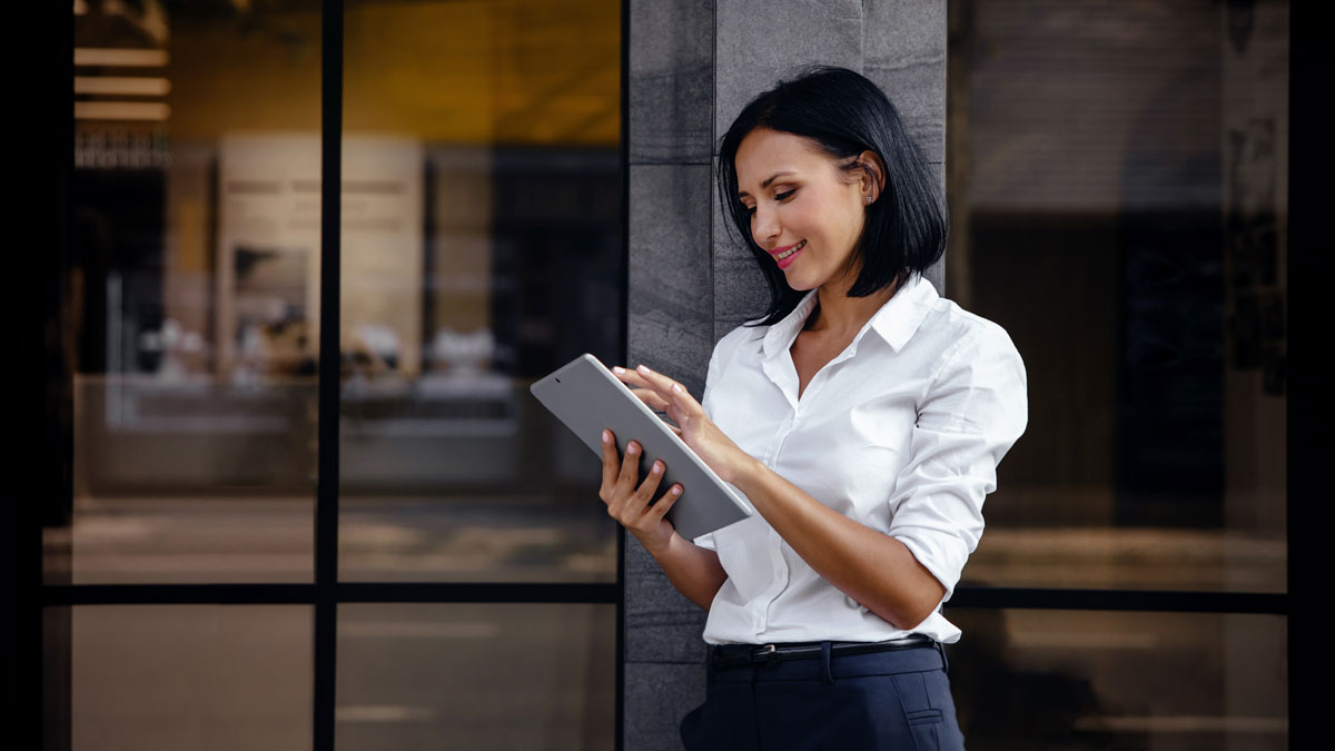Portrait of a Smiling Mixed Races Business Woman, Using Tablet outside the building