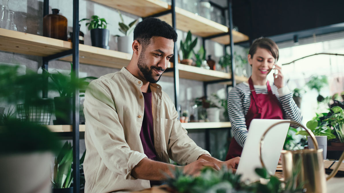 Shop assistants with laptop working in potted plant store, small business concept