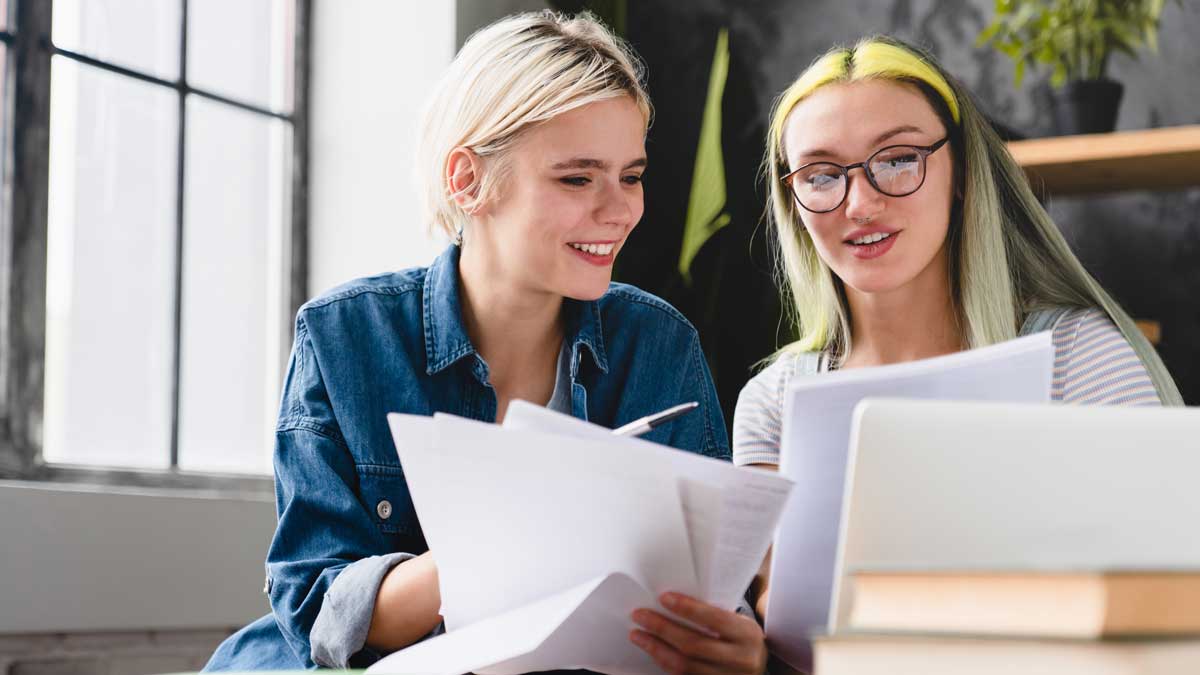 Paperwork, documents, bills and payments. Caucasian young coworkers female lesbian couple working together, dealing with financial papers cheques at home office