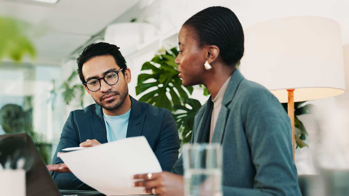 Office, team meeting and feedback for laptop, proposal and research notes with document for report. Man, woman and advice for small business, teamwork and collaboration for partnership or b2b project