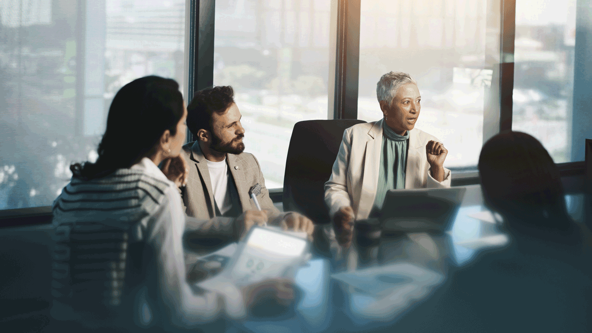 Discussion, group and mature woman with laptop, team and planning for financial growth in business. Corporate, accountant and monitoring performance with charts, people and info for productivity