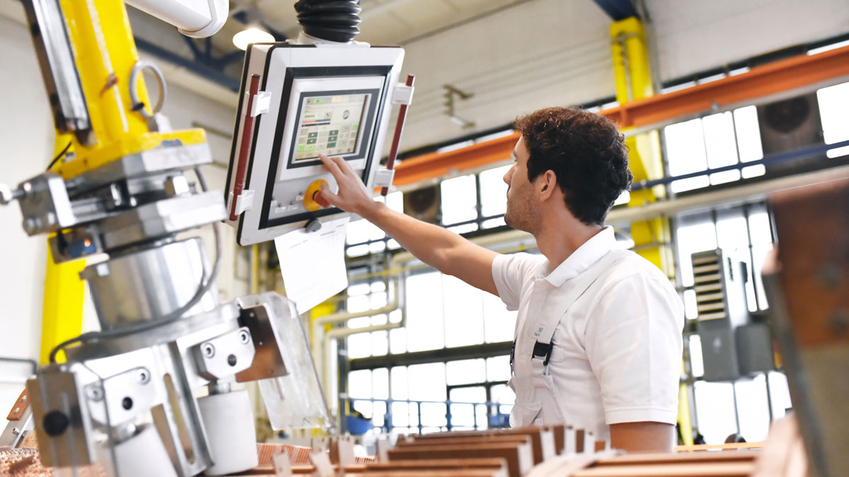 young mechanical engineering workers operate a machine for winding copper wire - manufacture of transformers in a factory