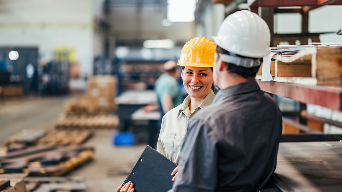 Two positive colleagues talking in heavy industry factory.