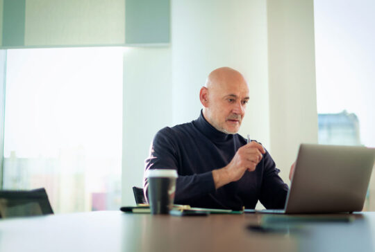 Middle aged businessman working on laptop in a modern office