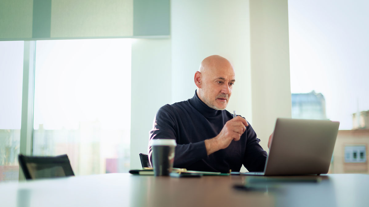 Middle aged businessman working on laptop in a modern office