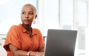 Thinking, online and black woman with laptop, serious and typing of ideas in office and copywriting. Writer, working and creative for website on desk, reading and confident in company and person