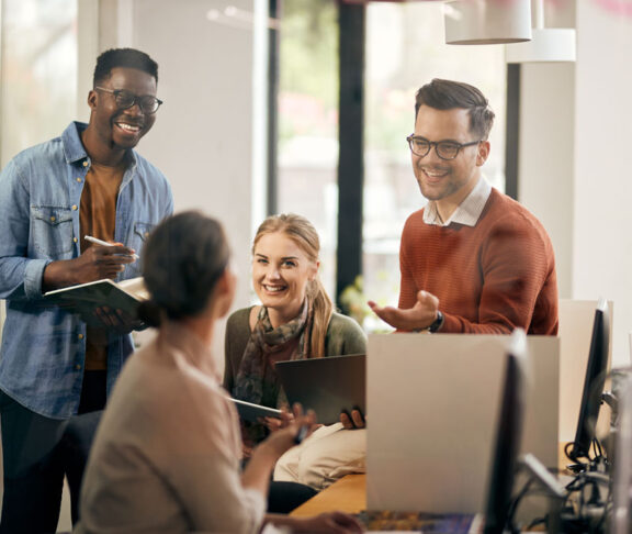 Young happy start-up team talking during business meeting in the office.