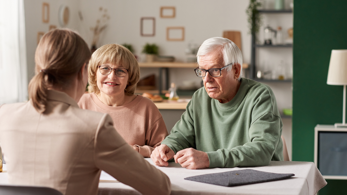 Senior couple sitting at the table with realtor and have a consultation about financial documents at home