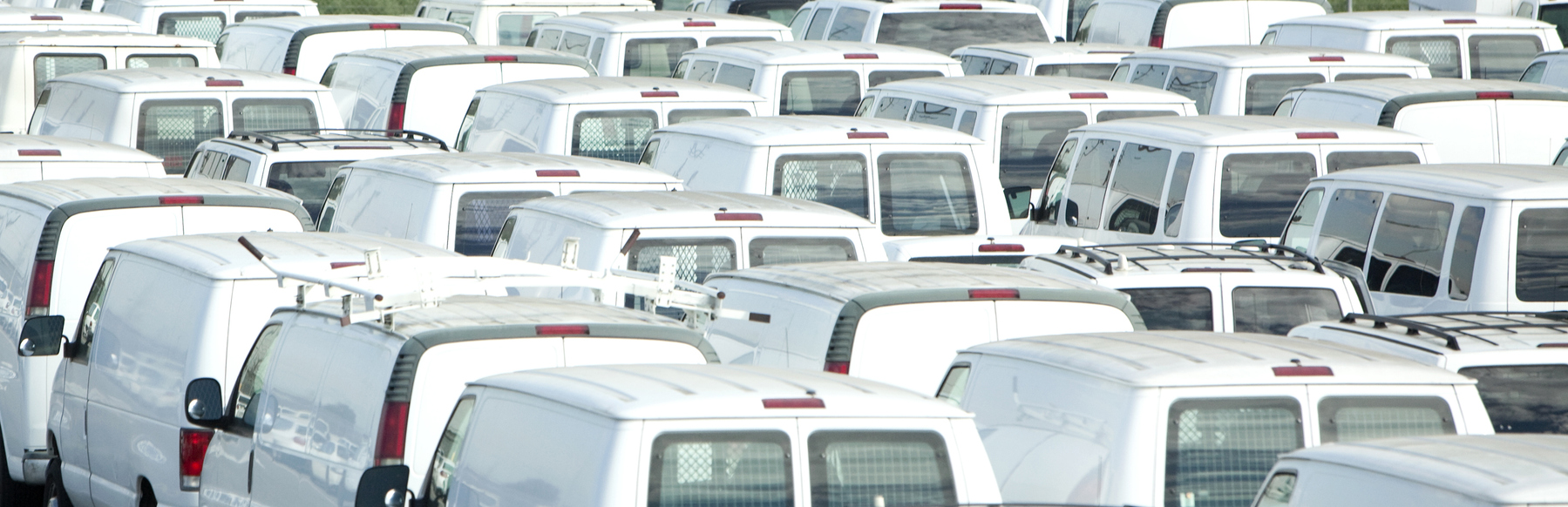 Rows of parked vans in a parking lot.