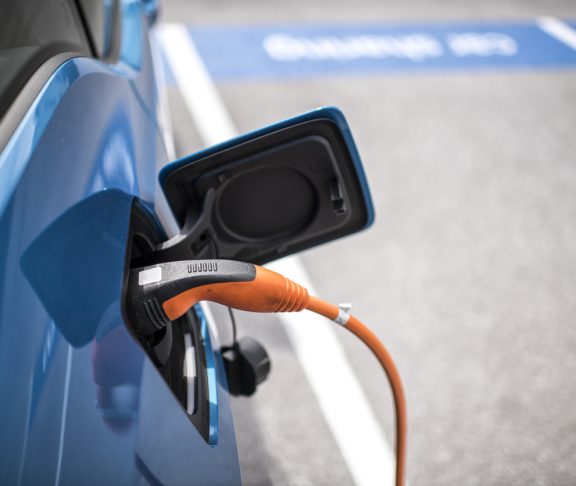 Power cord charging the electric car on the parking lot.