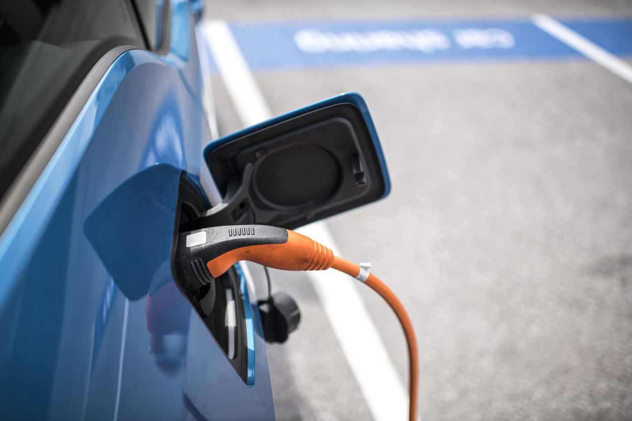 Power cord charging the electric car on the parking lot.