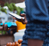 Extreme Nahaufnahme Bild zeigt die moderne NFC-Zahlungsmethode, mit Händen, die ein POS-Terminal und ein Mobiltelefon halten.