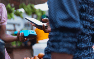 Extreme Nahaufnahme Bild zeigt die moderne NFC-Zahlungsmethode, mit Händen, die ein POS-Terminal und ein Mobiltelefon halten.
