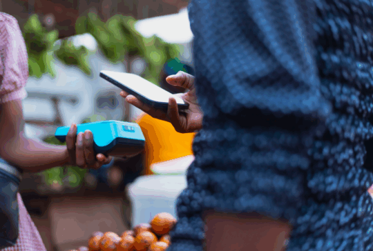 Extreme Nahaufnahme Bild zeigt die moderne NFC-Zahlungsmethode, mit Händen, die ein POS-Terminal und ein Mobiltelefon halten.