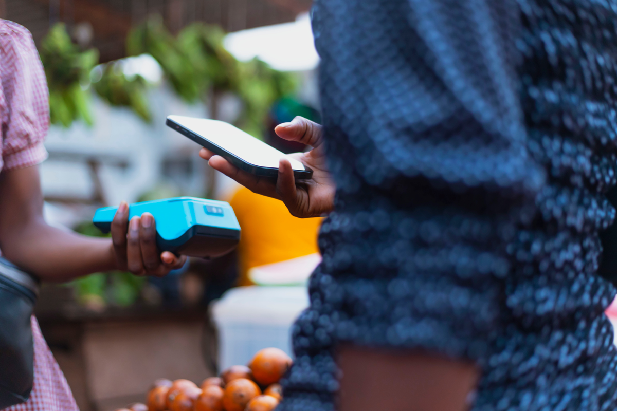 Extreme Nahaufnahme Bild zeigt die moderne NFC-Zahlungsmethode, mit Händen, die ein POS-Terminal und ein Mobiltelefon halten.