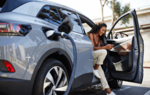 Smiling woman using smart phone at charging station