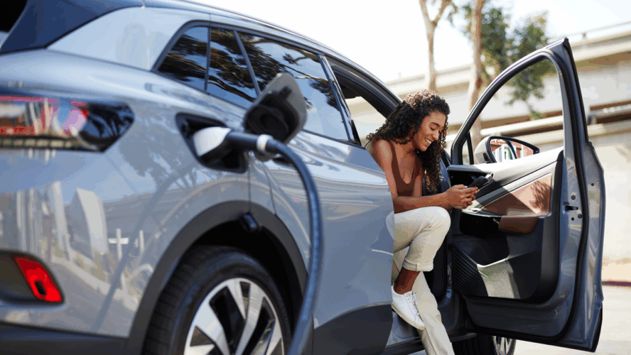 Smiling woman using smart phone at charging station