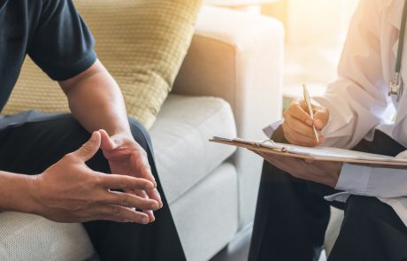 Doctor consulting male patient, working on diagnostic examination on men's health disease or mental illness, while writing on prescription record information document in clinic or hospital office